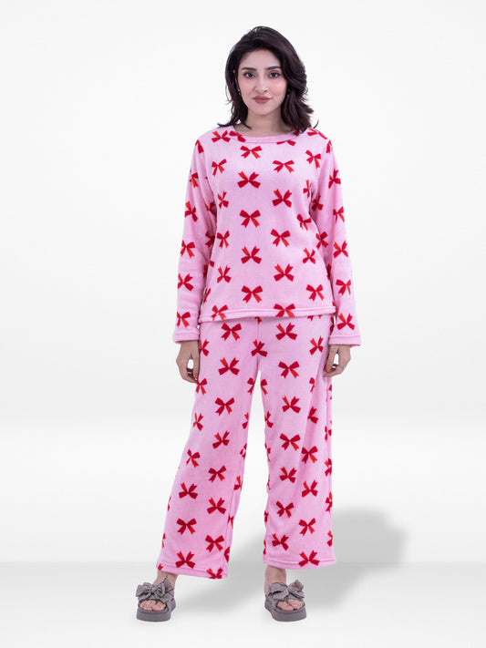 Woman wearing a pink pajama set with red bow pattern on a white background