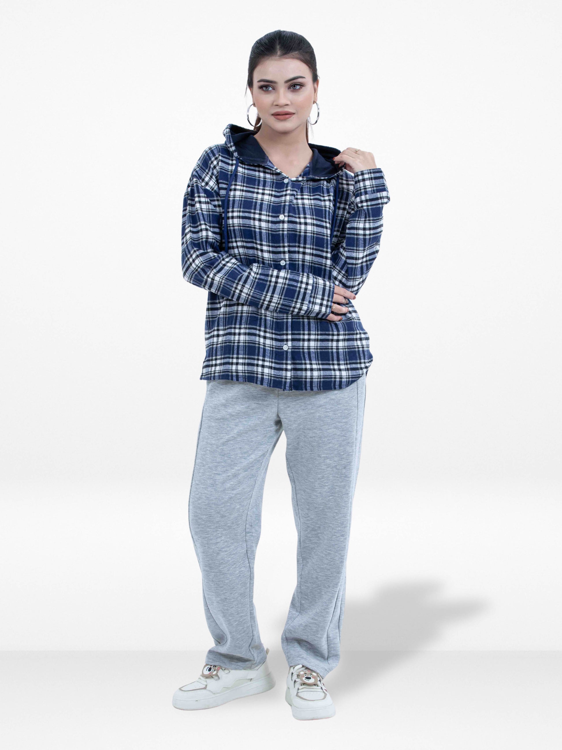 Woman wearing a blue plaid shirt and gray pants on a white background