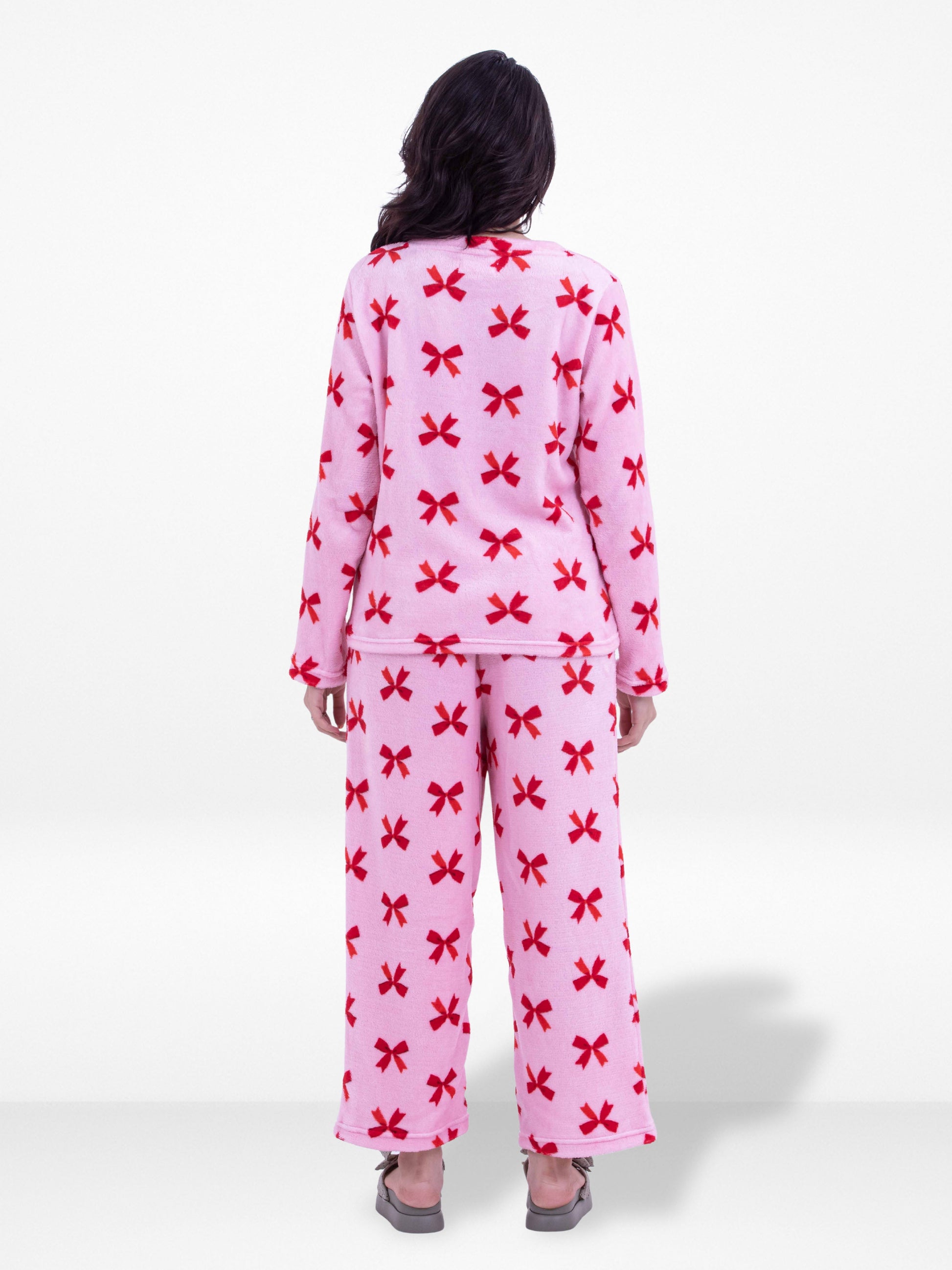 Person wearing pink pajamas with red bow pattern on a white background