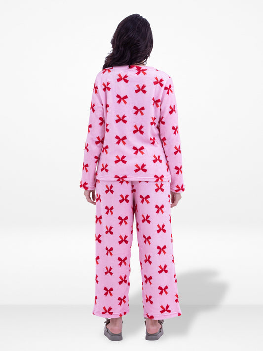 Person wearing pink pajamas with red bow pattern on a white background