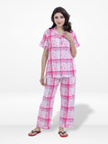Woman wearing a pink and white checkered pajama set on a white background